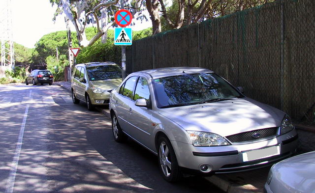 Imagen de la calle Llan de Gav Mar con los coches de los incvicos aparcados sobre la acera impidiendo su uso por parte de los peatones e ignorando la seal de prohibido aparcar (13 de mayo de 2009)